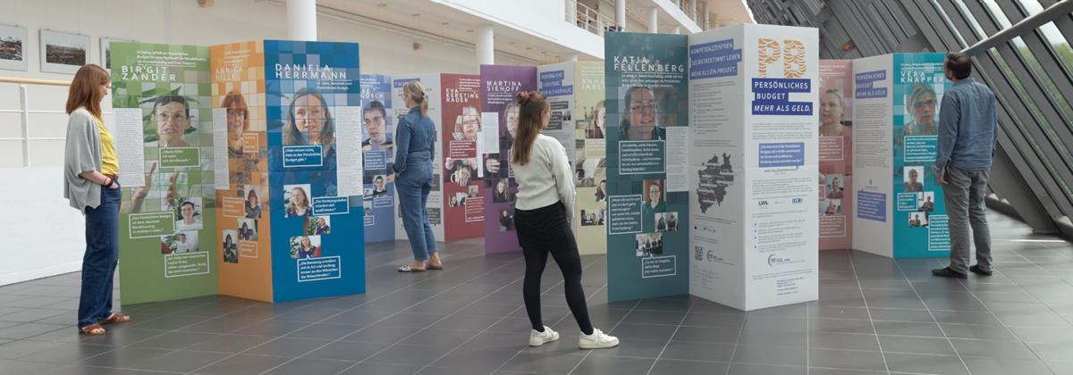 Die aufgebaute Wanderausstellung mit Personen dazwischen, die sie betrachten.