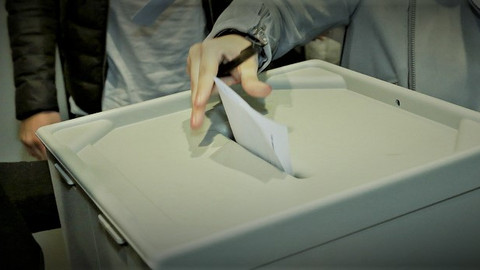 Eine Wahlurne in die ein Wahlzettel eingeworfen wird