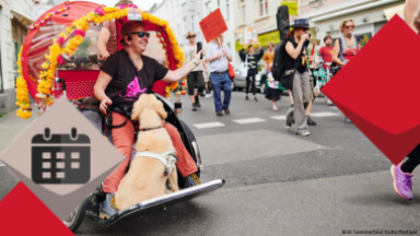 Eine Aufnahme von einer Mad Pride Parade aus den letzten Jahren. Eine Frau nimmt sitzend in einer Rikscha teil. Ihr Hund begleitet sie auf den Fußbrett.
