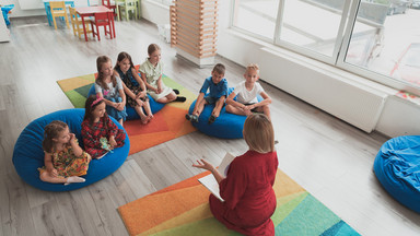 Die Frau und Kinder sitzen auf dem Boden im Raum