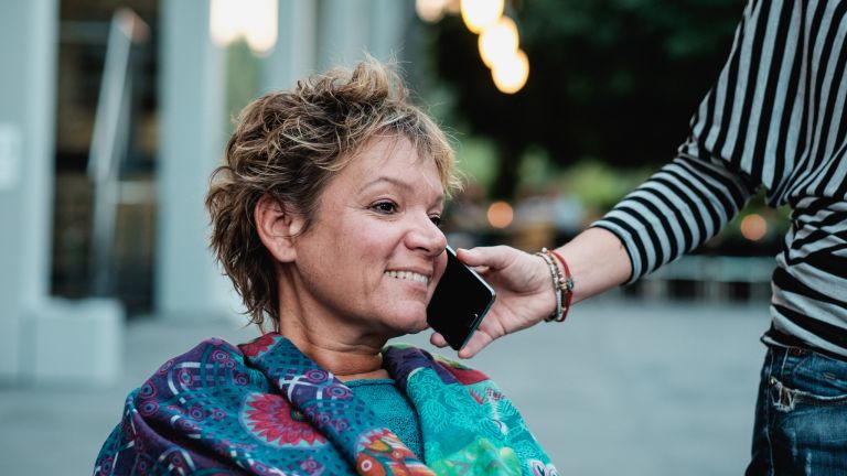 Assistent hält das Telefon für eine Frau mit Behinderung